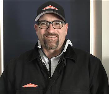 man with short brown hair, a bear and servpro hat on