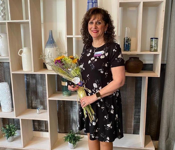 woman with black hair in a dress holding flowers