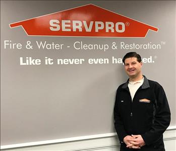 man with brown hair standing in front of a wall with the servpro logo on it